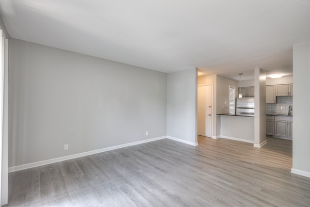 unfurnished living room featuring sink and light hardwood / wood-style flooring