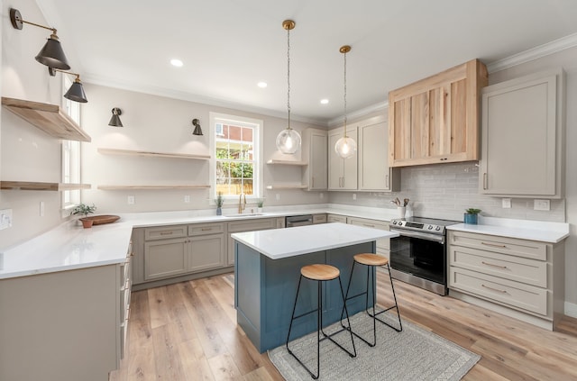 kitchen featuring appliances with stainless steel finishes, a breakfast bar, a center island, light hardwood / wood-style flooring, and sink