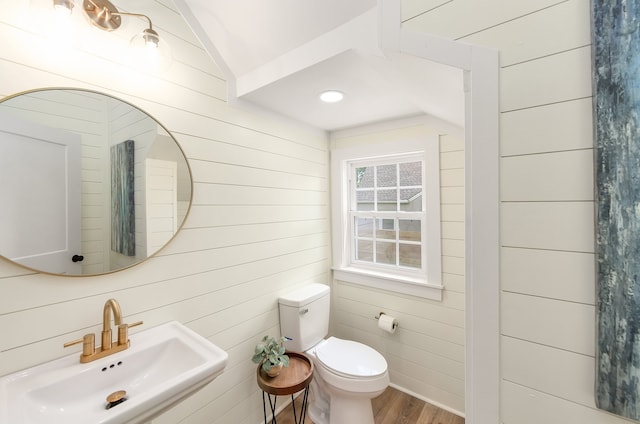 bathroom with wood-type flooring, vaulted ceiling, sink, and toilet