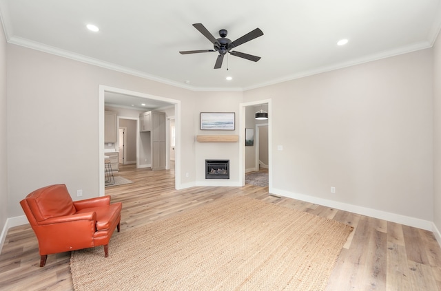 living room featuring ceiling fan, crown molding, and light hardwood / wood-style floors