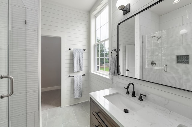 bathroom with tile patterned flooring, wood walls, walk in shower, and vanity