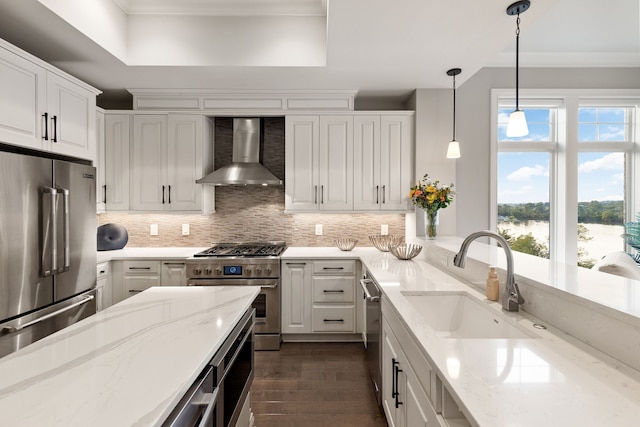 kitchen featuring sink, light stone counters, wall chimney exhaust hood, decorative backsplash, and premium appliances