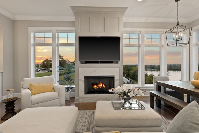 living room with a high end fireplace, ornamental molding, a chandelier, and hardwood / wood-style floors