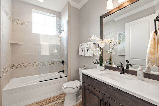 full bathroom with ornamental molding, hardwood / wood-style floors, toilet, vanity, and tiled shower / bath combo