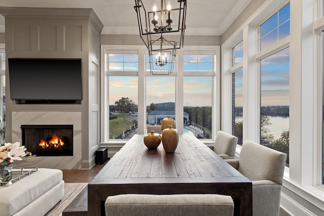 dining space with hardwood / wood-style floors, a fireplace, ornamental molding, and a water view