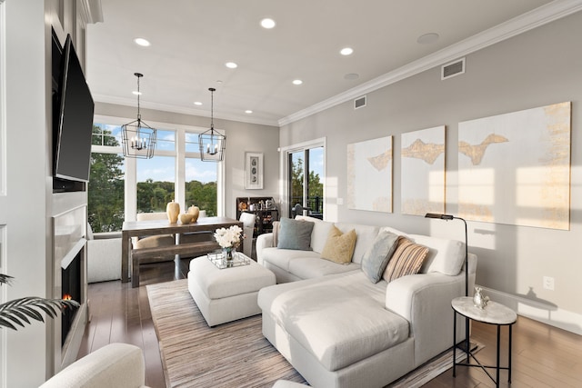 living room with hardwood / wood-style flooring, ornamental molding, and a chandelier