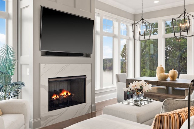 living room with a high end fireplace, ornamental molding, dark hardwood / wood-style flooring, and a healthy amount of sunlight