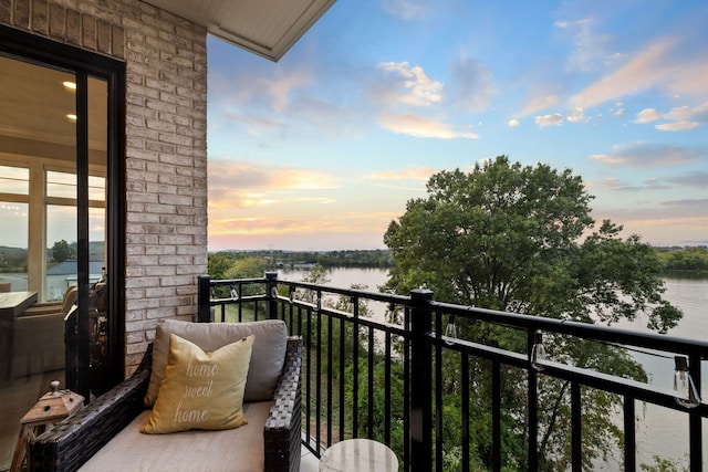 balcony at dusk featuring a water view