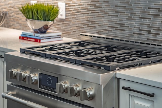 details featuring stainless steel gas range and tasteful backsplash