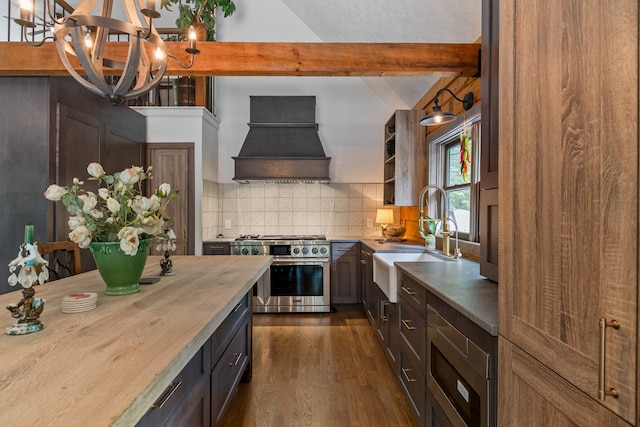 kitchen with dark wood-type flooring, range with two ovens, decorative light fixtures, premium range hood, and sink