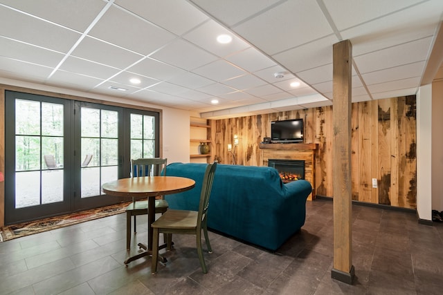 living room with a paneled ceiling and wood walls