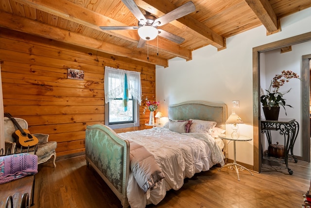 bedroom featuring wood-type flooring, beam ceiling, wood walls, ceiling fan, and wooden ceiling