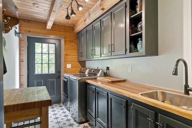 laundry room with cabinets, wood ceiling, sink, wood walls, and washer and clothes dryer