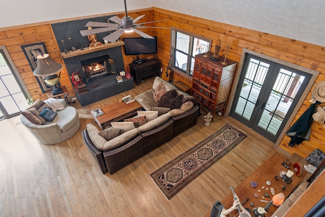 living room featuring wood walls, a textured ceiling, lofted ceiling, ceiling fan, and hardwood / wood-style floors