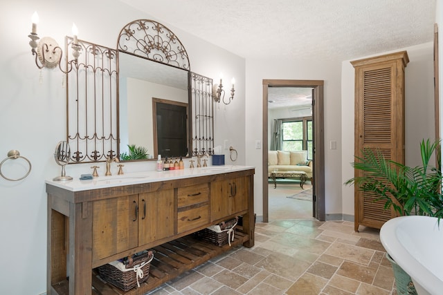 bathroom with a textured ceiling, a bath, and vanity