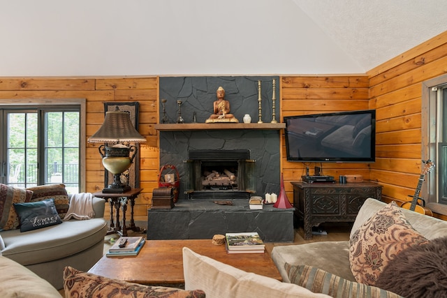 living room with a textured ceiling, a fireplace, wood walls, and vaulted ceiling