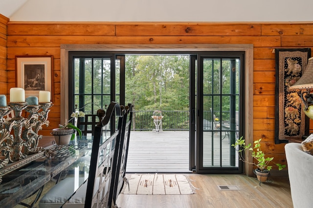 doorway featuring light hardwood / wood-style flooring, a wealth of natural light, and wooden walls