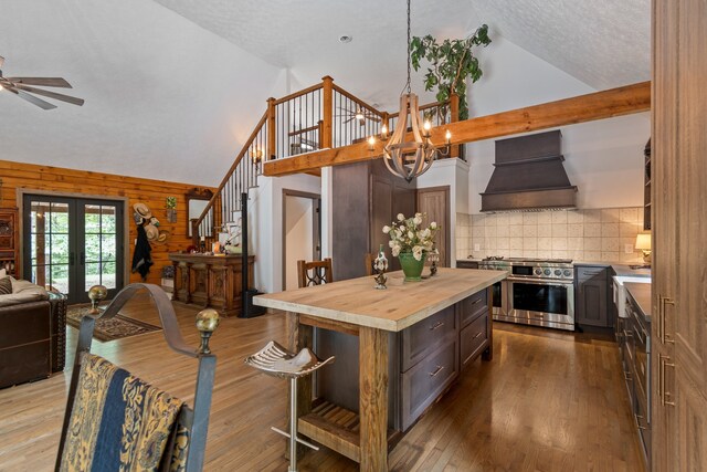 kitchen with premium range hood, wood walls, a kitchen island, range with two ovens, and hardwood / wood-style floors