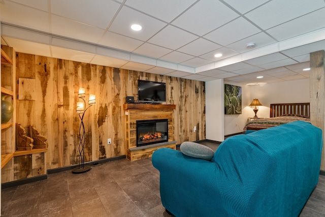 living room featuring a paneled ceiling, a fireplace, and wood walls