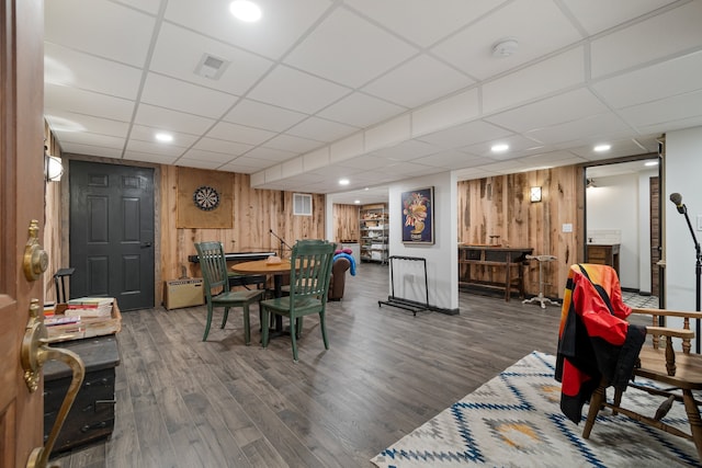 dining space featuring wooden walls, hardwood / wood-style floors, and a paneled ceiling