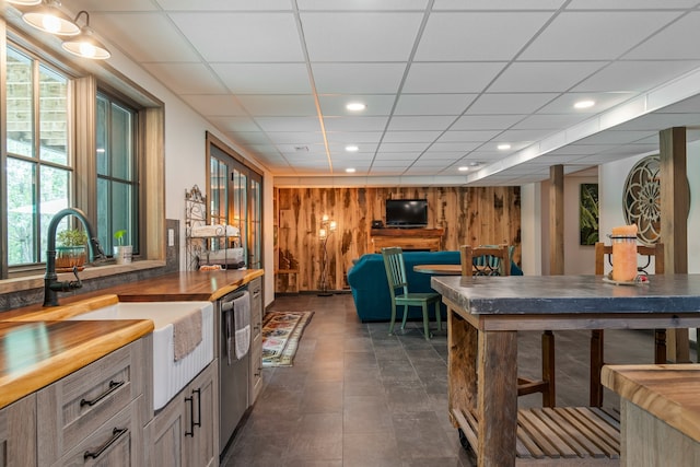 kitchen featuring a drop ceiling, wood walls, plenty of natural light, and sink