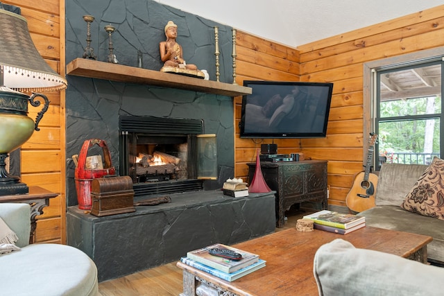 living room with lofted ceiling, wooden walls, hardwood / wood-style floors, and a fireplace