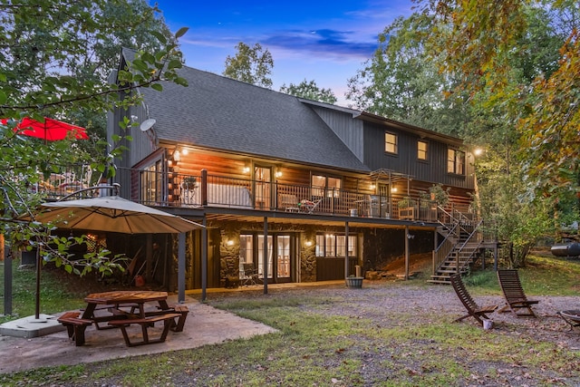 back house at dusk featuring a patio and a deck