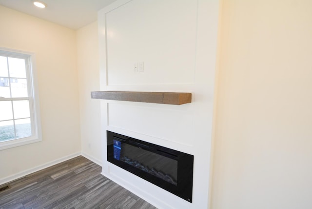 details featuring recessed lighting, visible vents, a glass covered fireplace, wood finished floors, and baseboards