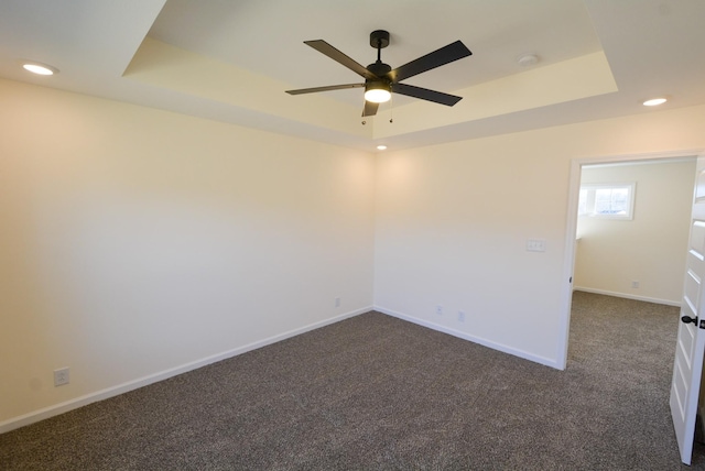 unfurnished room featuring ceiling fan, recessed lighting, baseboards, dark carpet, and a raised ceiling