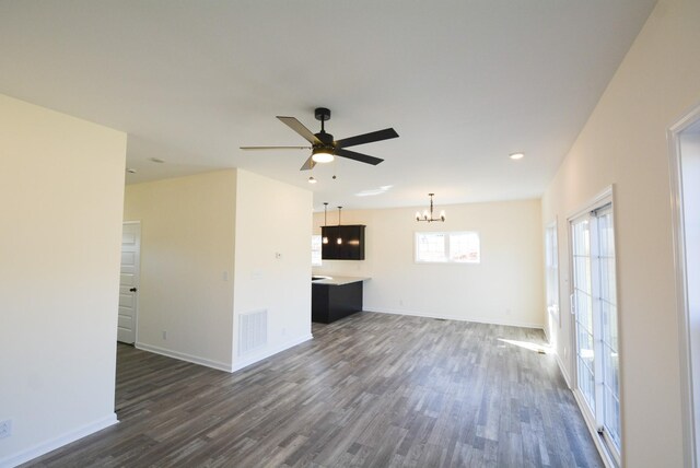 unfurnished living room featuring dark wood-style floors, visible vents, baseboards, and ceiling fan with notable chandelier