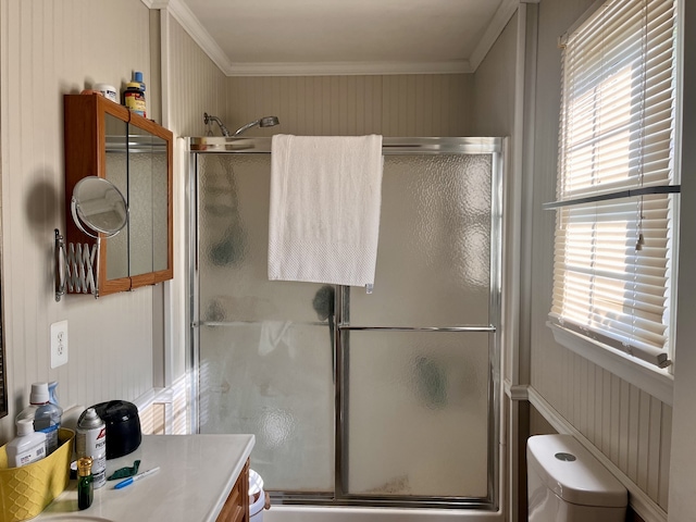 bathroom with a wealth of natural light, walk in shower, crown molding, vanity, and toilet