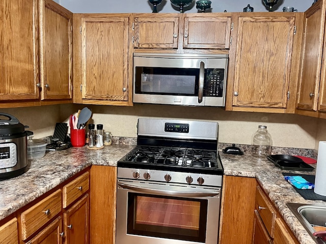 kitchen featuring appliances with stainless steel finishes, sink, and light stone counters