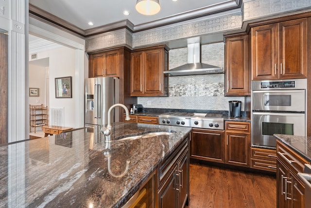 kitchen with dark wood-type flooring, sink, wall chimney range hood, appliances with stainless steel finishes, and ornamental molding