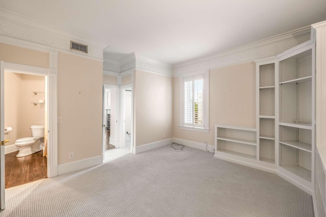 unfurnished bedroom with baseboards, ensuite bath, ornamental molding, carpet flooring, and visible vents