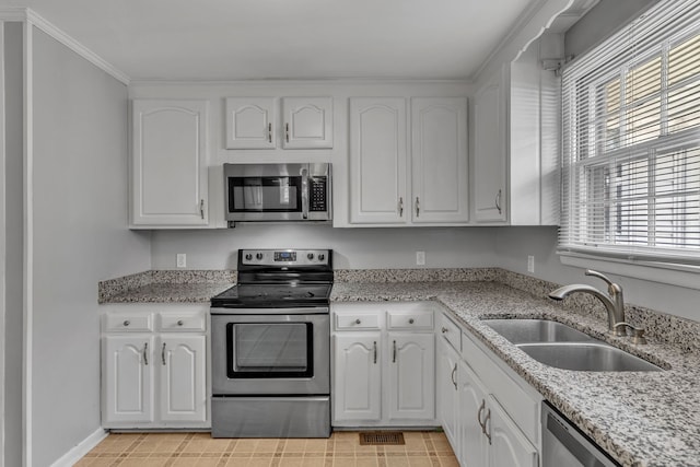 kitchen featuring light stone countertops, stainless steel appliances, sink, and white cabinetry