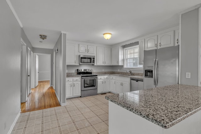 kitchen with light stone counters, stainless steel appliances, light wood-type flooring, and white cabinetry