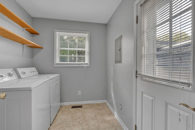 laundry area featuring light tile patterned floors, electric panel, and washing machine and clothes dryer