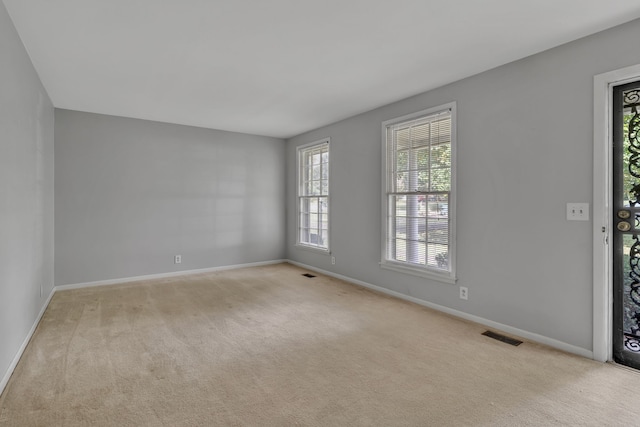 unfurnished room with light carpet and plenty of natural light