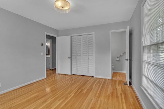 unfurnished bedroom with a closet, light wood-type flooring, and connected bathroom