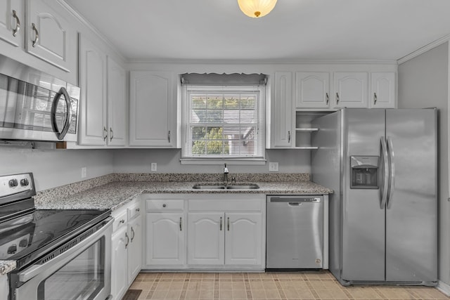 kitchen featuring stainless steel appliances, white cabinetry, light stone counters, and sink