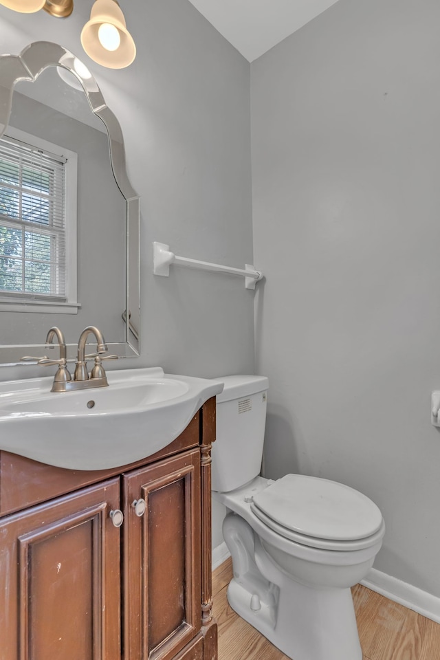 bathroom featuring wood-type flooring, vanity, and toilet