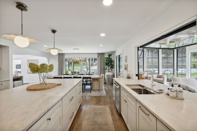 kitchen with dishwasher, sink, white cabinetry, hanging light fixtures, and dark hardwood / wood-style flooring