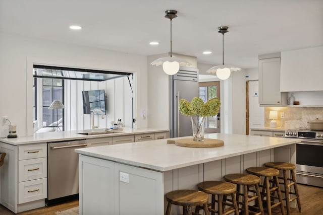 kitchen with white cabinets, a center island, appliances with stainless steel finishes, and hanging light fixtures