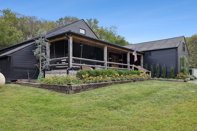 rear view of house featuring a lawn and a sunroom