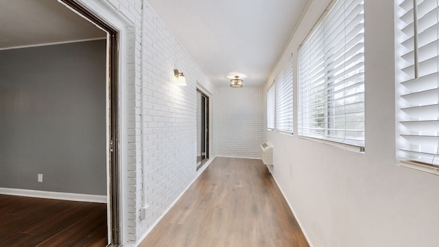 hall with dark wood-type flooring and brick wall