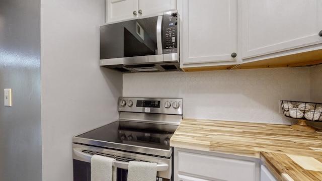 kitchen with backsplash, white cabinetry, butcher block countertops, and stainless steel appliances