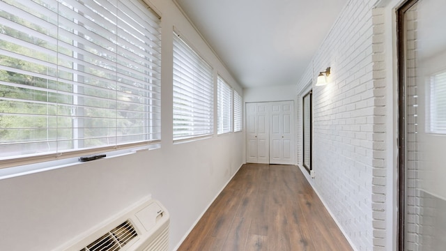 hallway featuring brick wall and dark hardwood / wood-style flooring