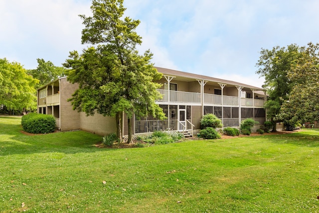 rear view of house featuring a lawn and a balcony