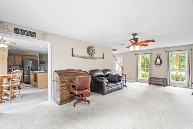 living room with ceiling fan, light colored carpet, and a textured ceiling