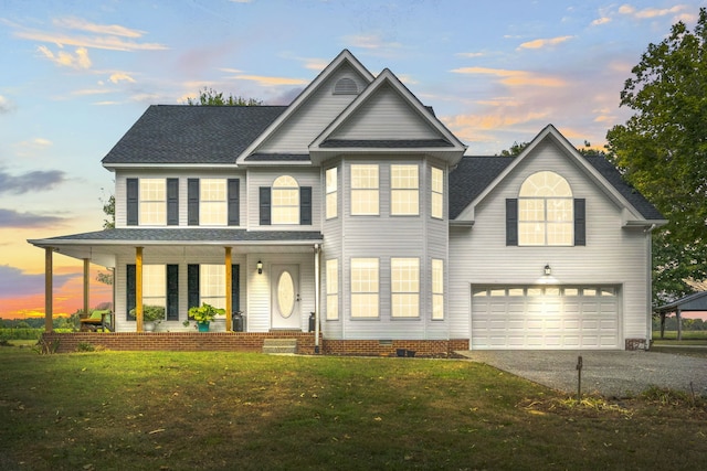 view of front of property with a garage, a porch, and a lawn